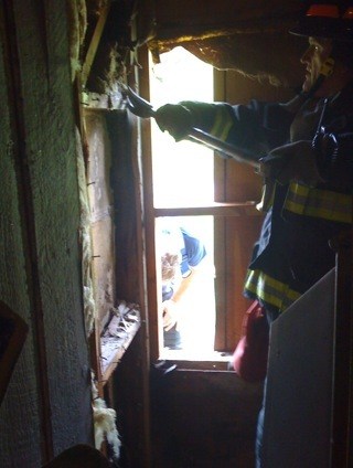 Captain Rick Anda works to open access to the interior wall just above the fire location.