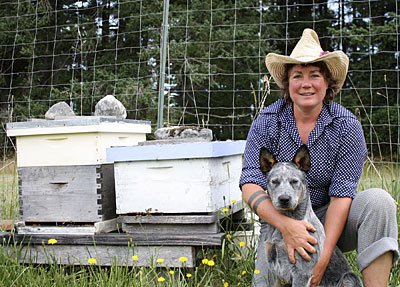 Farmer Rhonda Barbieri with her puppy Rudy Blue in front of her bee hives.
