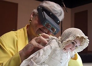 Antiques fair appraiser inspects  doll..