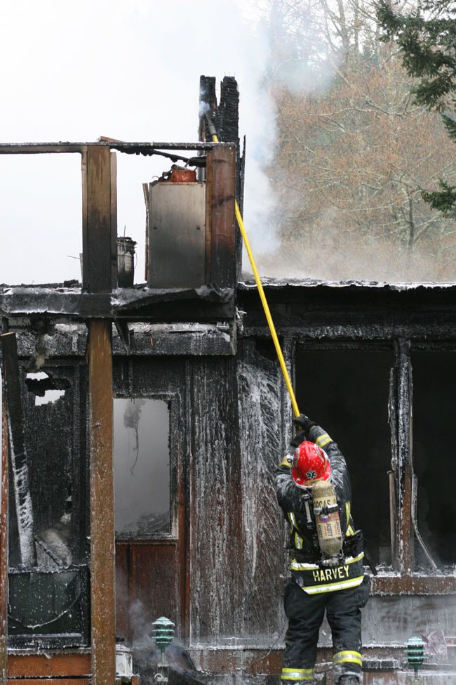 Lieutenant Richie Harvey working to pull down boards at the house fire.