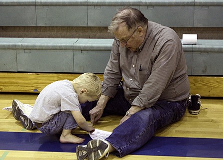 Ed Sutton helps his grandson Sam Sutton fold an airplane.
