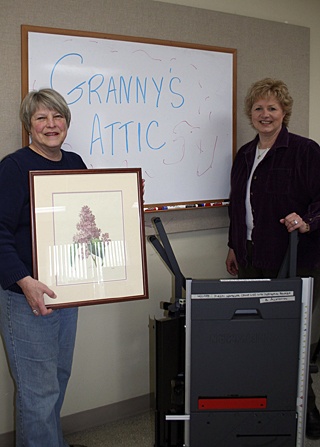 Jane Heisinger with a painting and Michele Streich with a table saw that will be for sale at Granny's Attic on April 18.