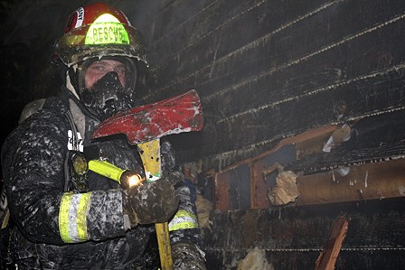 Volunteer firefighter Rich Harvey working on putting out the house fire on Nov. 16.