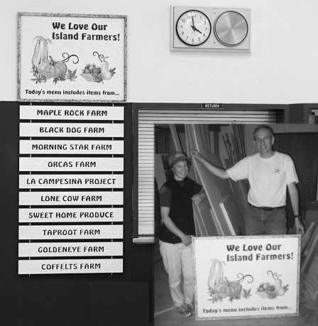 Tracy and Chris Betcher display the sign now hanging in the school cafeteria that recognizes local farmers who provide products for school lunches during the school year.