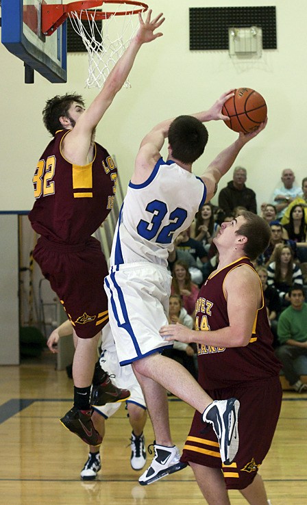 Daniel Janssen (32) driving for a layup against Lobos Mica Arps (32) and Leland Nopson (44).