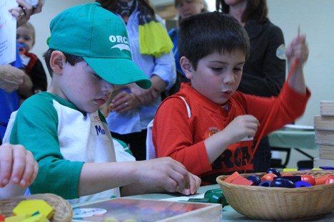 Kindergartners-to-be carefully lace wooden beads