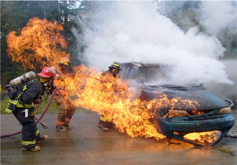 Photo: Live Fire training on Whidbey Island. Lt. Kevin McCoy directs firefighters Mike Macksey and Ted McKey on car fire technique.