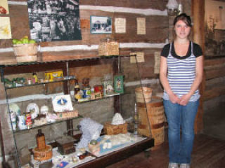 Orcas Island Historical Museum aide Lea Bossler stands in front of pioneer store items.
