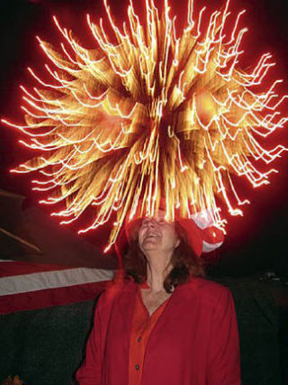 Don’t try this at home! Suzanne Lyons-Downie of Orcas Arts wears a “Glorious” hat at the Deer Harbor Fireworks show
