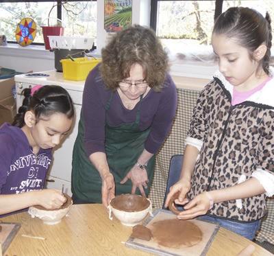 Penny Sharpe Skye helps students Soeth Quintero and Jeiri Velazquez learn the techniques of bowl making.