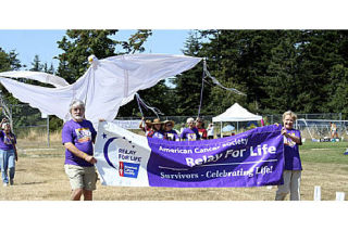 Bob Sheidler and Judy Resch hold the Relay for Life banner as they lead the “Survivor’s Lap” at the Orcas Relay for Life. See more pictures on page A8.
