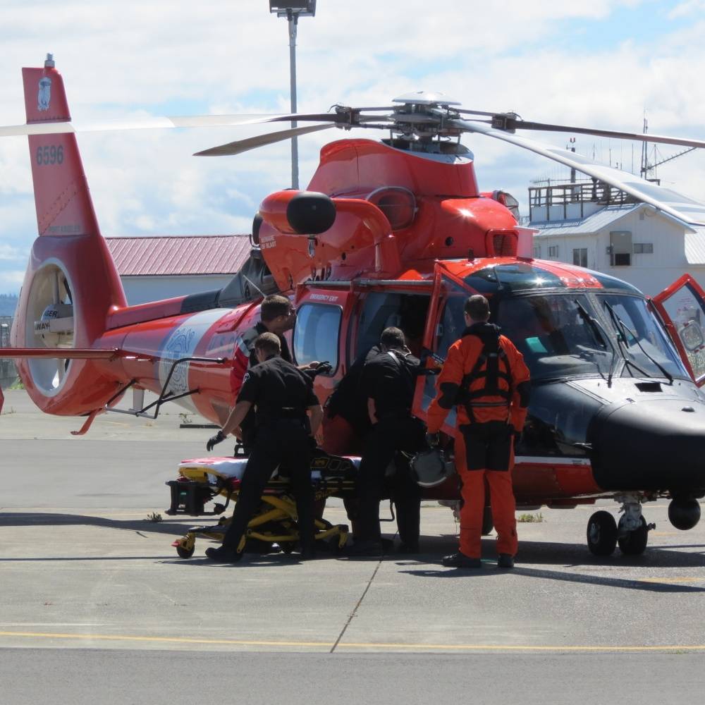 Contributed photo/Petty Officer 2nd Class Ali Flockerzi U.S. Coast Guard District 13                                A Coast Guard helicopter aircrew from Air Station Port Angeles transfers an unresponsive individual to local Emergency Medical Service personnel after recovering him the water near the Strait of Juan de Fuca on July 10.