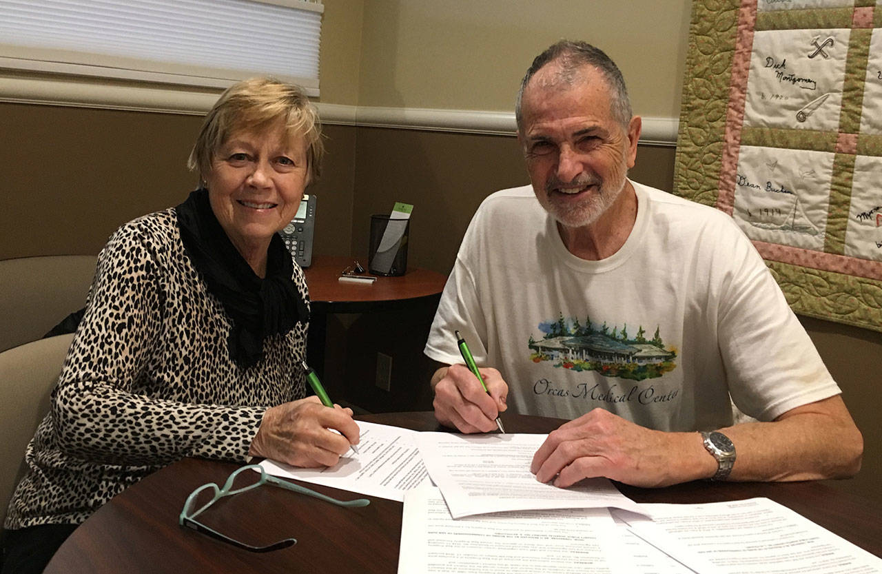 Leslie Murdock, president of the Orcas Medical Foundation and Richard Fralick, president of the board of commissioners of the district, signing the sale documents.