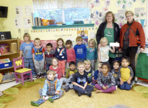 Kaleidoscope Preschool Director Amber Paulsen and Kaleidoscope kids receive $750 from Secretary of the Emmanuel Parish St. Agnes Guild, Joanne Cundy.