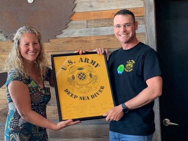 Heather Spaulding/staff photo                                At right: Executive Director Stephanie Buffum presented with a 569th plaque by Divemaster Thomas Kneipp.