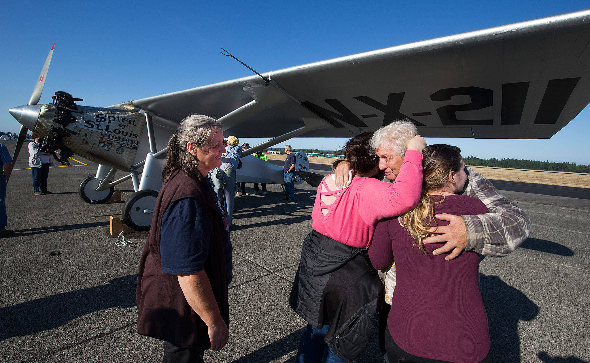 As his wife, Heather, looks on, John Norman gets a hug from his daughter Amber Nelson and granddaughter Ashlee Nelson (right) after his replica of the Spirit of St. Louis flew for the first time from Arlington Municipal Airport on July 28. (Andy Bronson / The Herald)