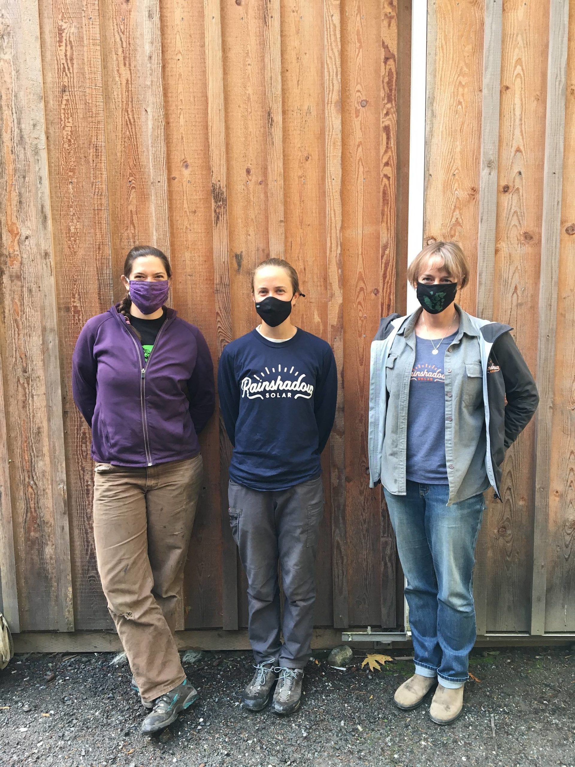 Laura Kussman/staff photoElectrician trainees Gaelyn Moore, Tessa Ormenyi and owner Chris Wolfe outside the Rainshadow Solar supplies barn near Guthrie Cove