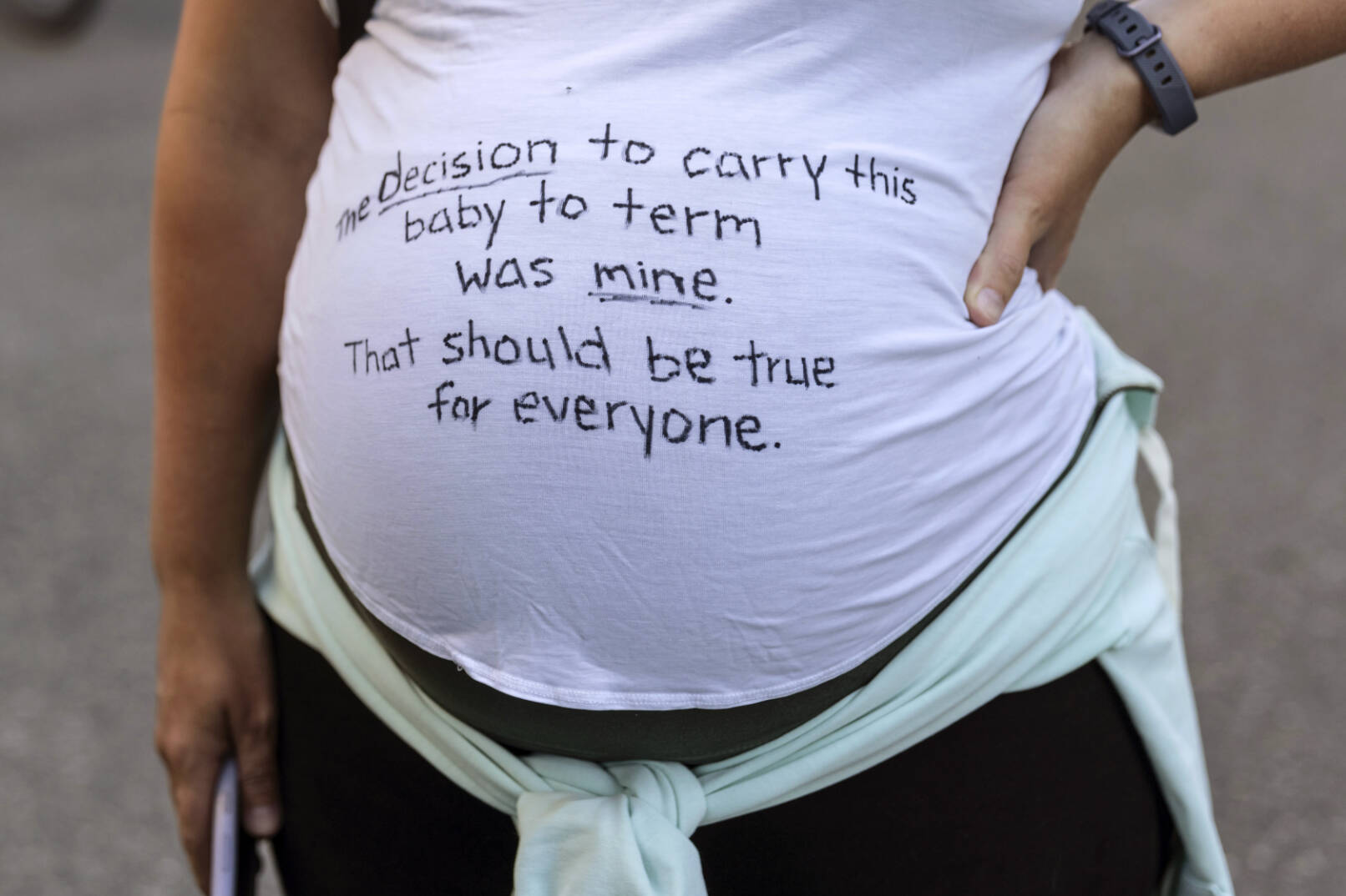A pregnant protester is pictured with a message on her shirt in support of abortion rights during a march, Friday, June 24, 2022, in Seattle. The U.S. Supreme Court's decision to end constitutional protections for abortion has cleared the way for states to impose bans and restrictions on abortion — and will set off a series of legal battles. (AP Photo/Stephen Brashear)