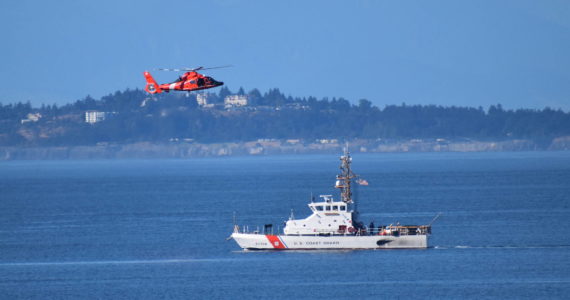US Coast Guard Cutter Swordfish stands by the scene of the vessel sinking as a Coast Guard helicopter flies overhead.