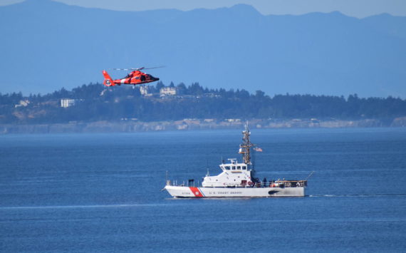 US Coast Guard Cutter Swordfish stands by the scene of the vessel sinking as a Coast Guard helicopter flies overhead.