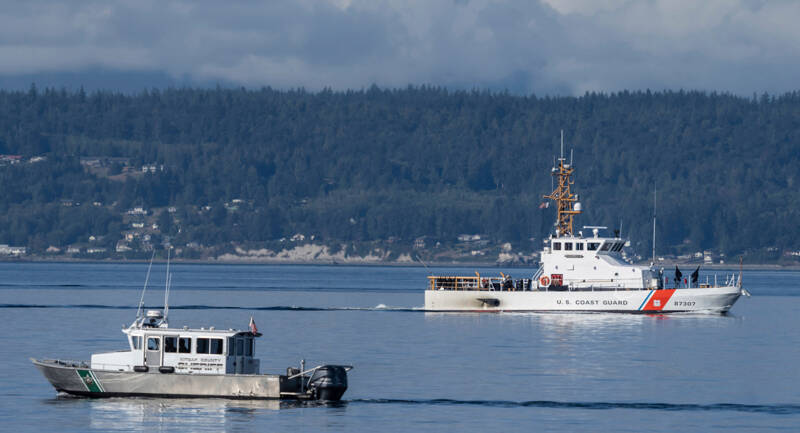 A U.S. Coast Guard boat and Kitsap County Sheriff boat search the area Monday near Freeland on Whidbey Island north of Seattle where a chartered floatplane crashed the day before. The plane was carrying 10 people and was en route from Friday Harbor to Renton. (Stephen Brashear/The Associated Press)