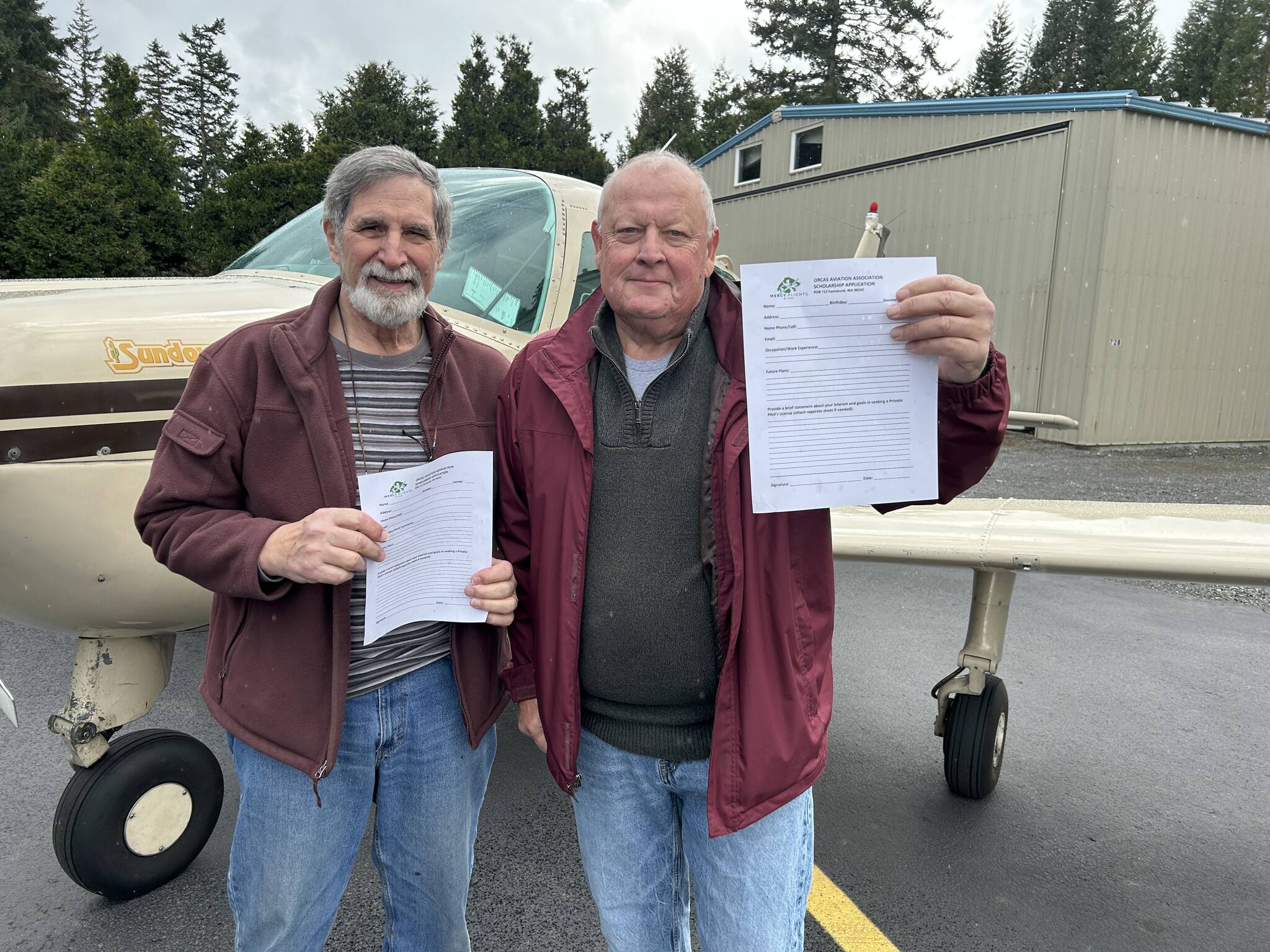 Jack Becker (left) Secretary/Treasurer of the Orcas Aviation Association and Rick Fant President of Airhawks Flying Club holding up the Scholarship Application form.