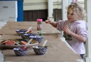 A small one enjoys decorating her cookie.