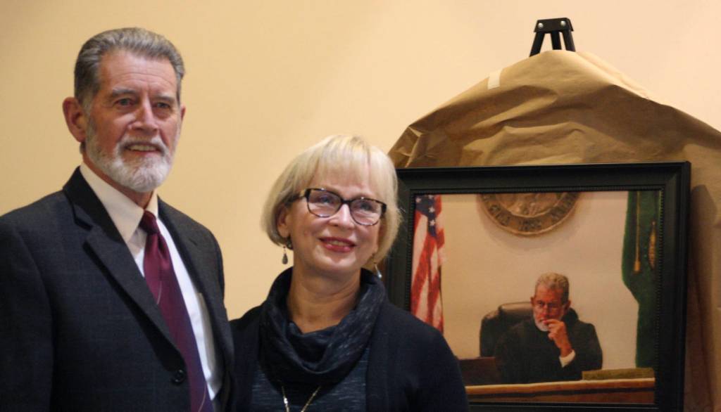 Staff photo/Hayley Day                                San Juan County Superior Court Judge Donald Eaton and his wife Sheryl smile in front of a portrait painted by Barnaby Zall, a local attorney.
