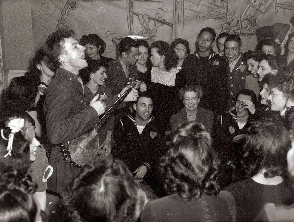 Pete Seeger entertaining Eleanor Roosevelt (center), honored guest at a racially integrated Valentines Day party marking the opening of a Canteen of the United Federal Labor, CIO, in then-segregated Washington, D.C., 1944.