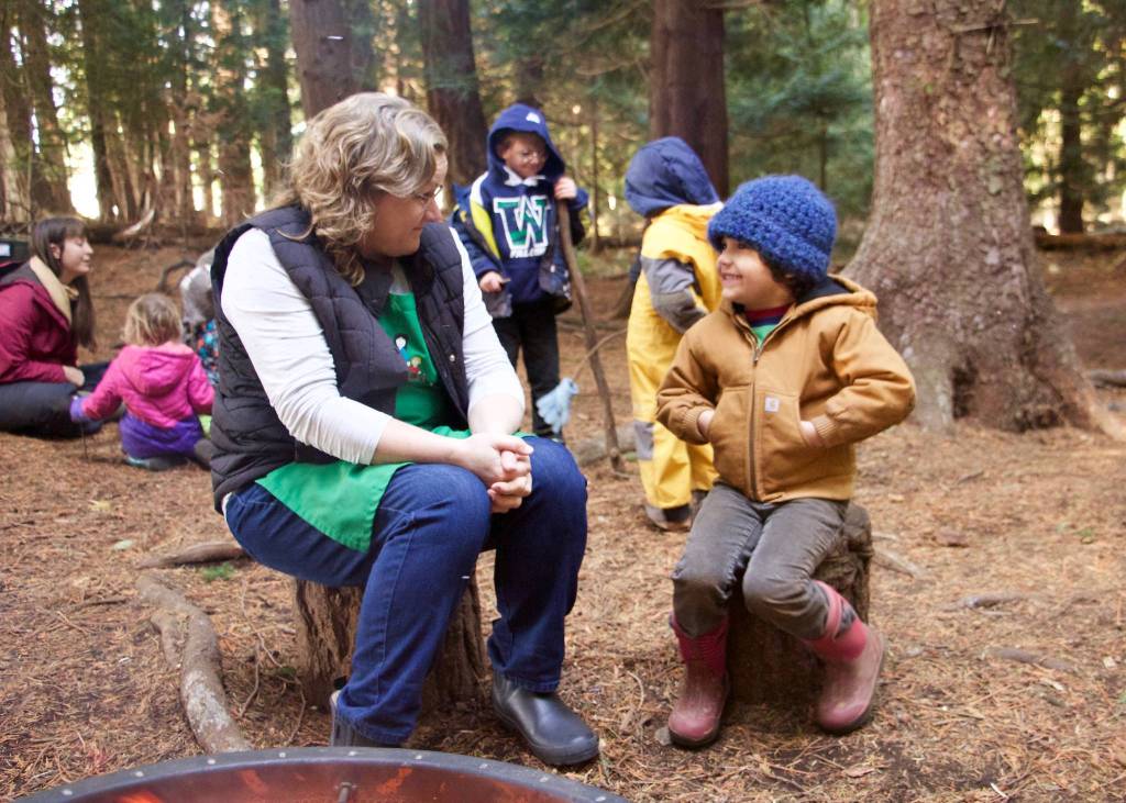 Amber Paulsen, Kaleidoscopes director, connects with forest school student Archer around the lunchtime campfire in the woods of Camp Orkila.