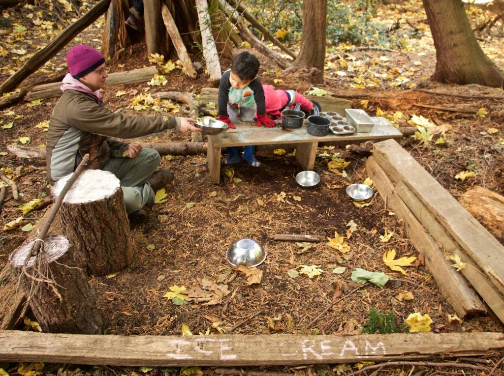 Lead teacher Daquilante shares sprinkles with a student during playtime in the ice cream shop, otherwise known as the well-use mud kitchen.