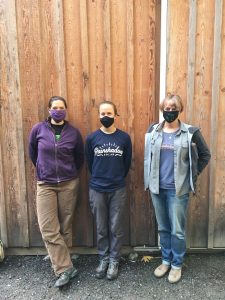 Laura Kussman/staff photoElectrician trainees Gaelyn Moore, Tessa Ormenyi and owner Chris Wolfe outside the Rainshadow Solar supplies barn near Guthrie Cove