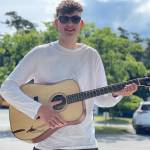 Contributed photo
Luke Knapp happily holds his creation. Luke inlaid an island and Orca whale scene in the soundboard of his guitar along with custom perfling, binding, and rosette.