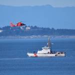 US Coast Guard Cutter Swordfish stands by the scene of the vessel sinking as a Coast Guard helicopter flies overhead.