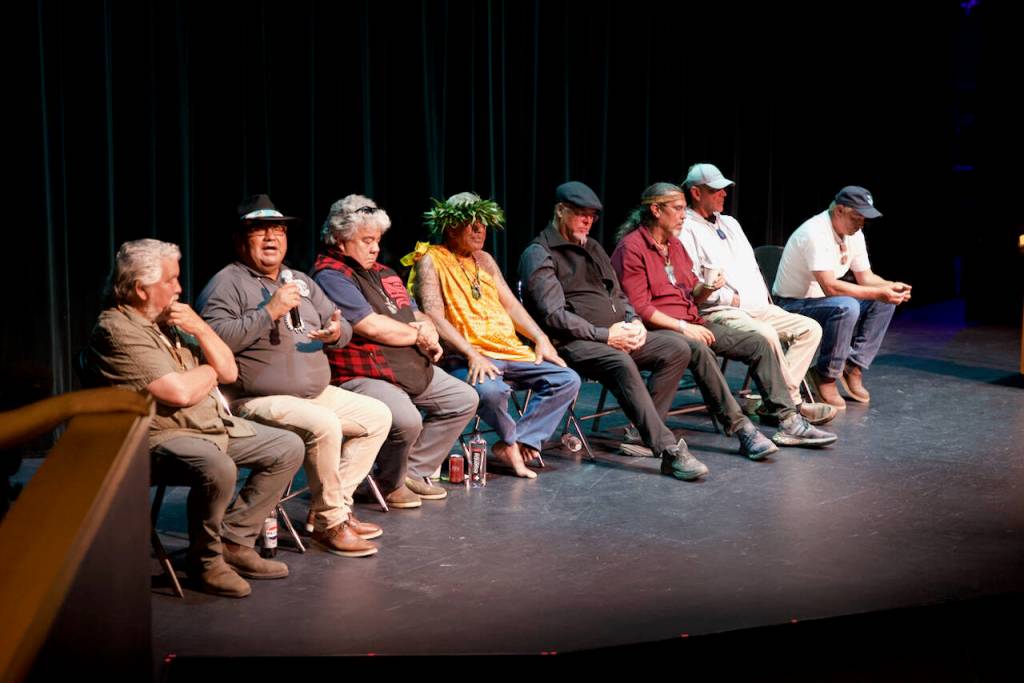 Darrell Kirk photo.
Shannon F. Wheeler (Nez Perce) speaks with the gathering at Orcas Center. Left to right: Guujaw (Haida), Shannon F. Wheeler (Nez Perce), Miles Richardson (Haida), Kimokeo Kapahulehua (Maui, Hawaii), Christian White (Haida), Mike Jones (Haida), Jay Julius (Lummi); and Dana Wilson (Lummi).