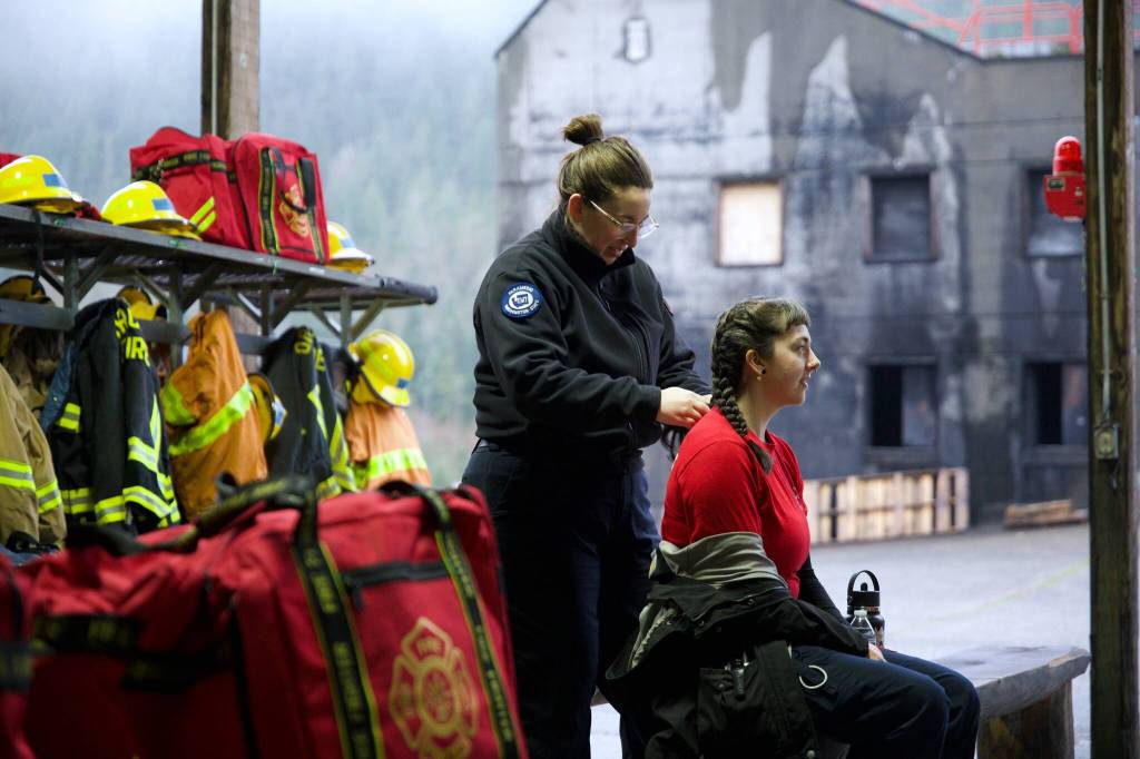 LT Amie Stevens (paramedic, firefighter, instructor) is braiding the hair of Bee Schermerhorn.